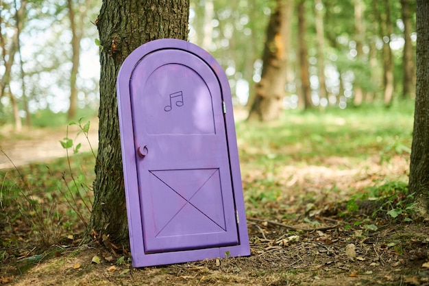 Porta pequena de conto de fadas encostada no tronco de árvore na floresta pequeno objeto de arte do país das maravilhas