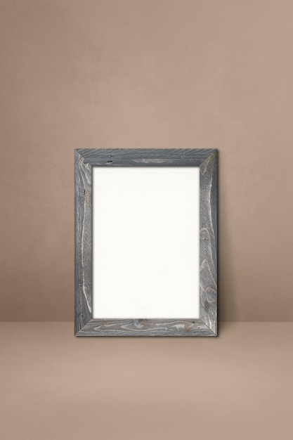 Foto porta-retrato de madeira encostado em uma parede bege. modelo de maquete em branco