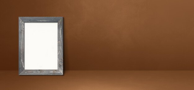 Porta-retrato de madeira encostado em uma parede marrom. Modelo de maquete em branco. Banner horizontal