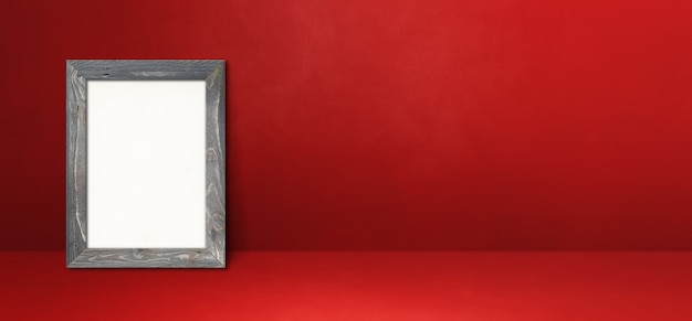 Porta-retrato de madeira encostado em uma parede vermelha. Modelo de maquete em branco. Banner horizontal