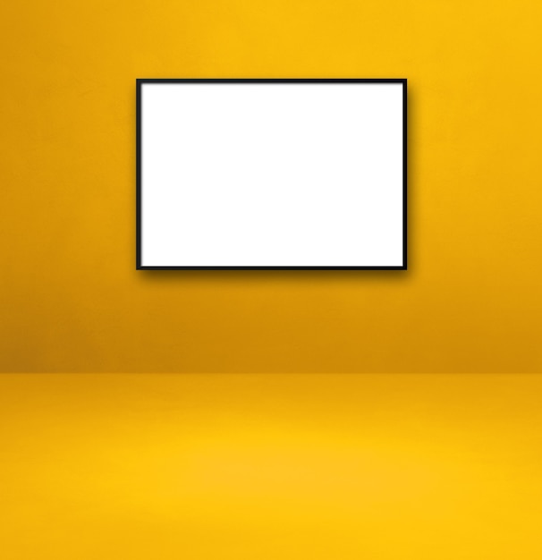 Porta-retrato preto pendurado em uma parede amarela. Modelo de maquete em branco