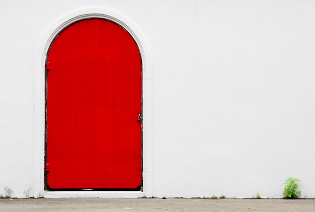 Porta vermelha antiga em um muro de concreto branco