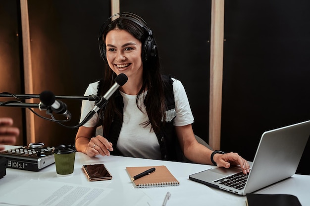 Portait de atractiva joven presentadora de radio hablando en el micrófono mientras modera un show en vivo