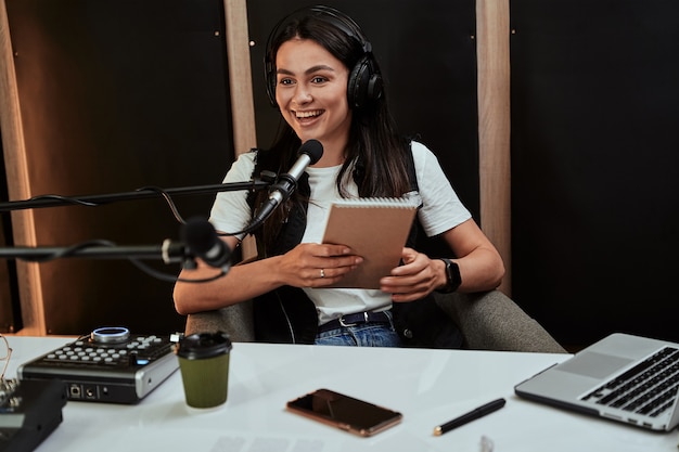 Portait de atractiva joven presentadora de radio sosteniendo un guión con aspecto emocional mientras habla en