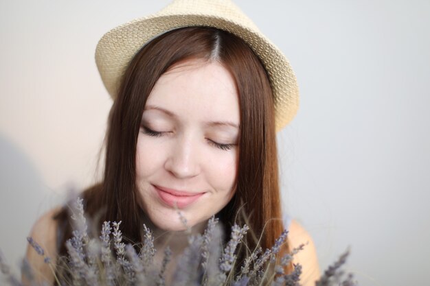 Portait de uma bela jovem usando um chapéu de verão e segurando flores de lavanda