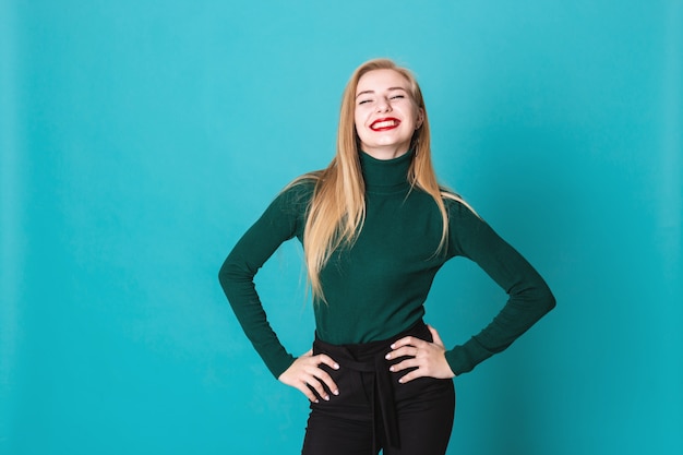 Portait de la feliz mujer rubia de pie sobre un fondo azul