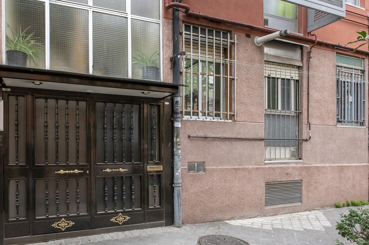 Foto portal de um edifício com porta pintada de preto e detalhes em latão dourado e fachada avermelhada