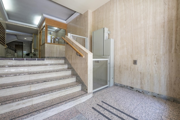Portal de um edifício residencial com escadas de mármore e elevador hidráulico para pessoas com problemas de mobilidade