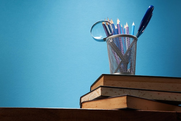 Foto portalápices con lupa y tijera en pila de libros