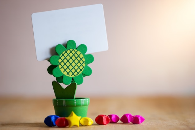 Foto portapapel porta tarjeta verde girasol en forma y estrellas de papel multicolor en mesa de madera.