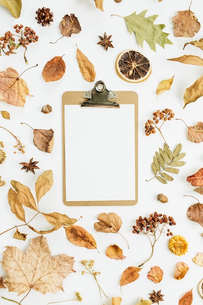 Portapapeles con papel en blanco sobre la superficie seca de las hojas de otoño de otoño