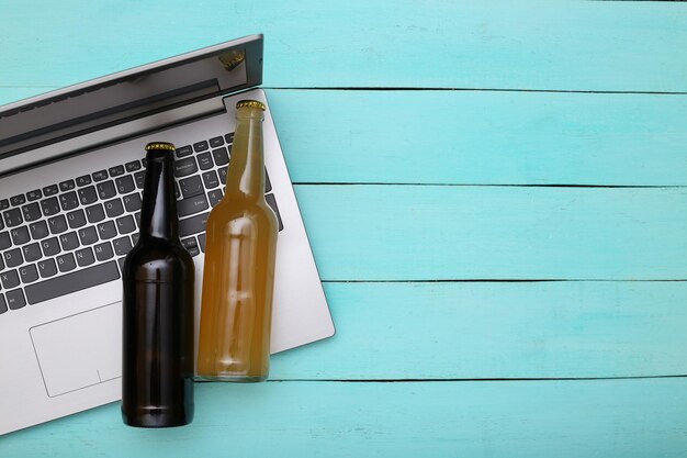 Portátil y botellas de cerveza sobre un fondo de madera azul. Vista superior