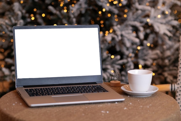 Portátil en una cafetería atmosférica de invierno con el telón de fondo de un árbol de Navidad Trabajo remoto