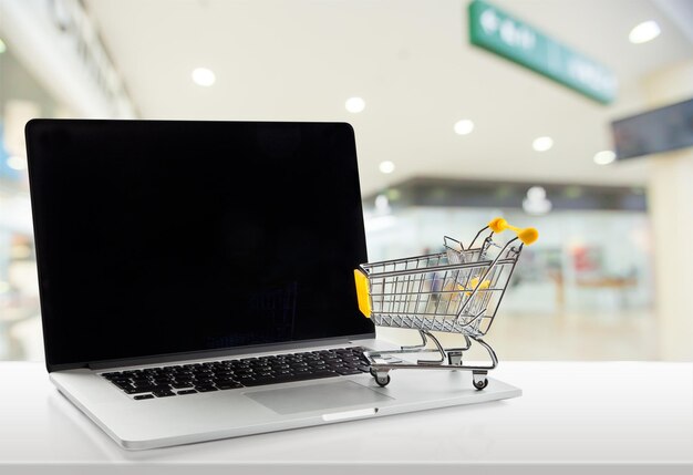Portátil y carrito de compras en mesa de madera