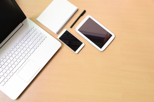 Foto portátil do caderno do computador com tabuleta digital e smartphone branco na mesa de madeira. na sala de negócios