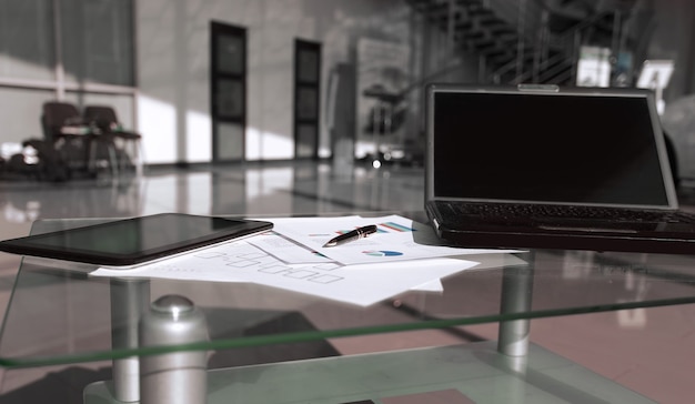 Foto portátil y documentos financieros en un escritorio en una oficina espaciosa