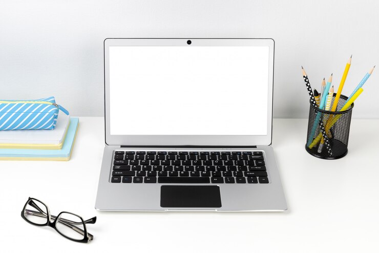 Foto portátil, gafas y papelería en mesa moderna blanca