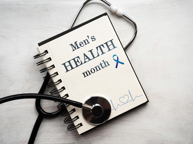 Portátil con el mes de la salud masculina y un estetoscopio sobre fondo blanco.