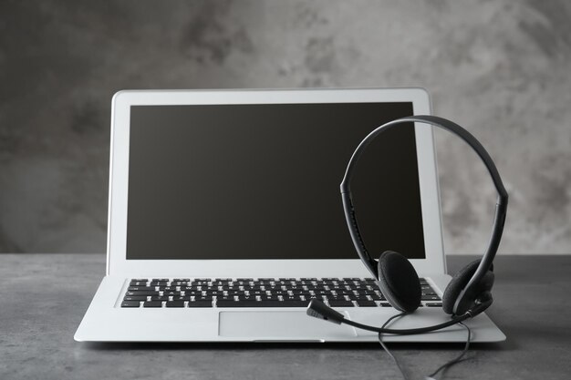 Portátil moderno y auriculares en mesa gris