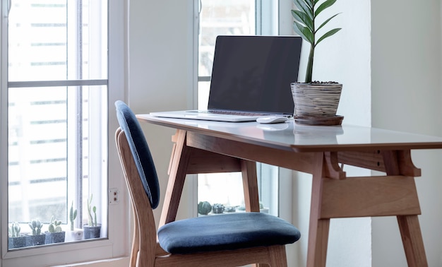 Portátil de pantalla en blanco sobre mesa de madera en casa moderna.