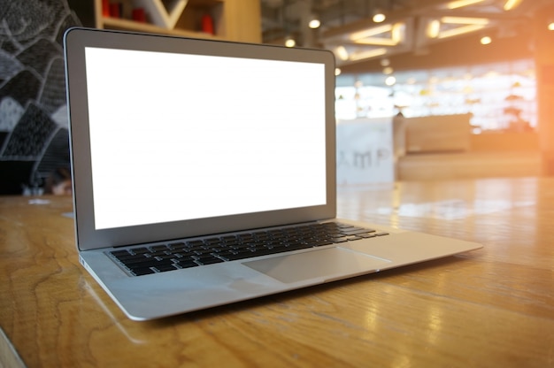 Portátil con pantalla en blanco sobre la mesa de madera delante de coffeeshop café - concepto de tecnología