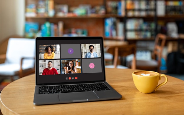 Portátil con pantalla de videollamada en la mesa del café