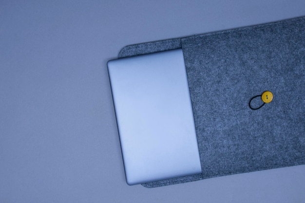 Portátil plateado cerrado en una funda protectora sobre un fondo gris Vista superior