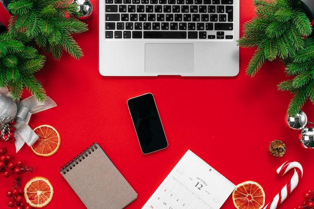 Portátil con ramas de árbol de piel y decoraciones navideñas en vista superior roja