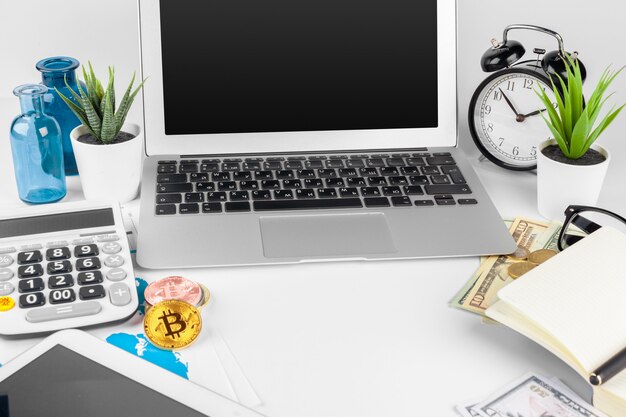 Portátil sobre la mesa cerca de dólares y bitcoins en la oficina