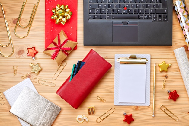Portátil, tarjetas de crédito, monedero y decoración navideña. Compras navideñas en línea, compra de regalos