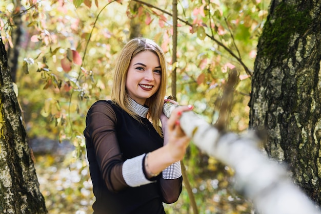 Porteait feminino no parque outono. beaurtiful mulher de vestido preto posando com árvores amarelas