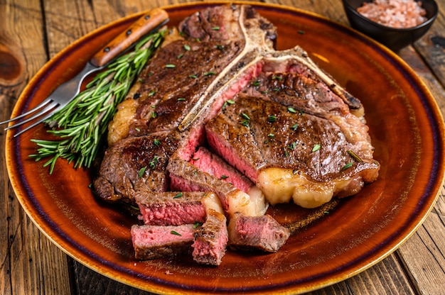 Porterhouse asado a la barbacoa o filete de carne de vacuno de hueso t en un plato rústico. fondo de madera. Vista superior.