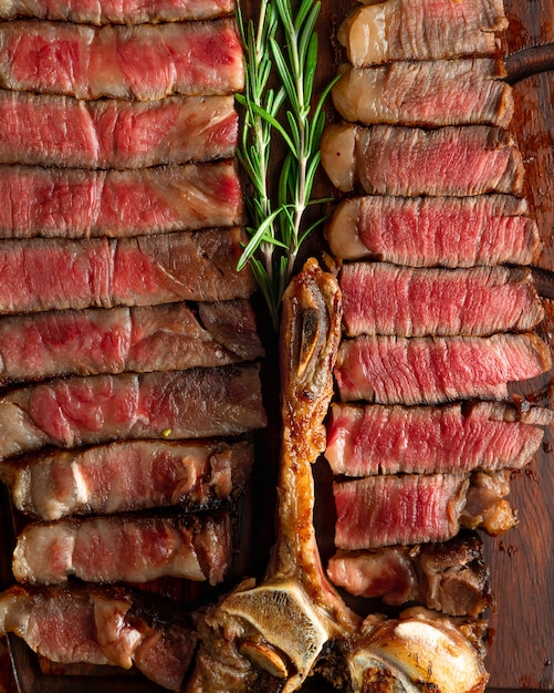 Foto porterhouse steak in stücke geschnitten serviert auf holzbrett, detailansicht. von oben geschossen. hochformat