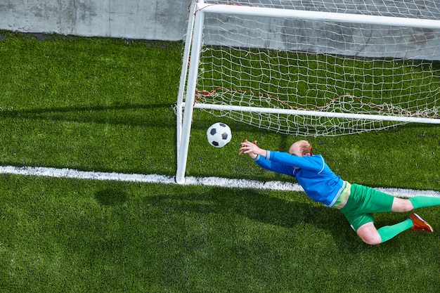 Portero de fútbol haciendo buceo guardar en verde fuild