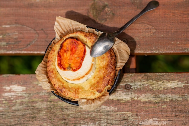 Portion Auflauf mit Käse und Tomaten auf einem hölzernen Hintergrund von oben