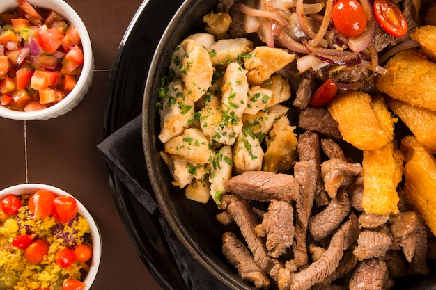 Portion Fleisch mit Pommes und gebratener Yucca, Zwiebel mit Gemüse und Paprika