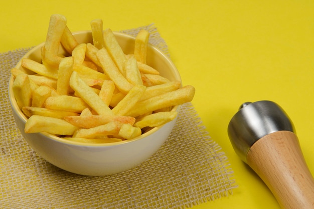 Portion Kartoffelpommes in Keramikschale auf gelb