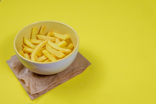 Portion Kartoffelpommes in Keramikschale auf lokalem gelbem Hintergrund