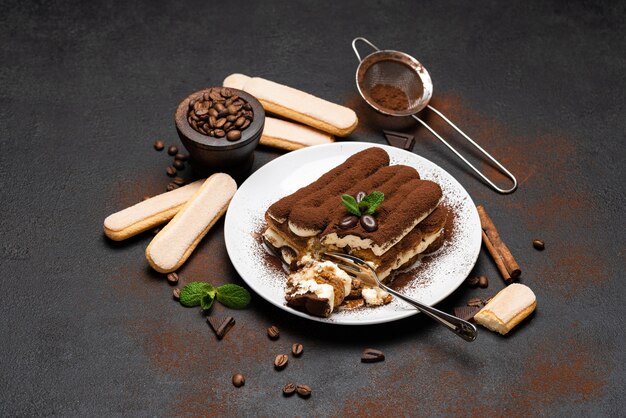 Portion klassisches Tiramisu-Dessert und Savoiardi-Kekse auf Betonhintergrund