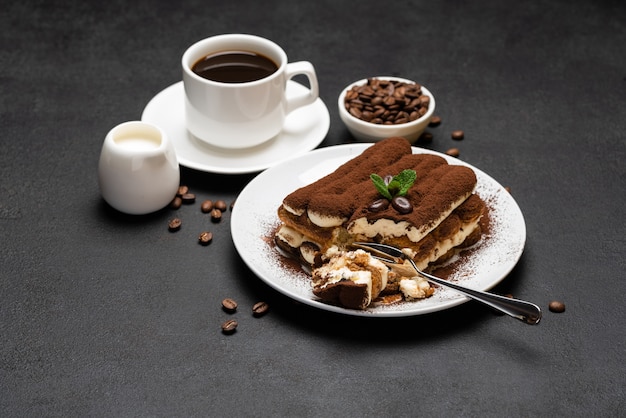 Portion klassisches Tiramisu-Dessert und Tasse frischen Espressokaffee auf Betonhintergrund oder Tisch