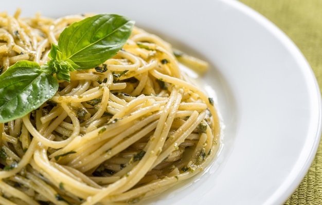 Portion Nudeln mit Pesto-Sauce und Basilikum