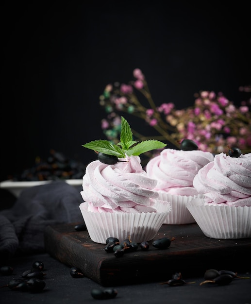 Portionierte Fruchtmarshmallows in einem Pappbecher auf einem schwarzen Holzbrett köstliches Dessert