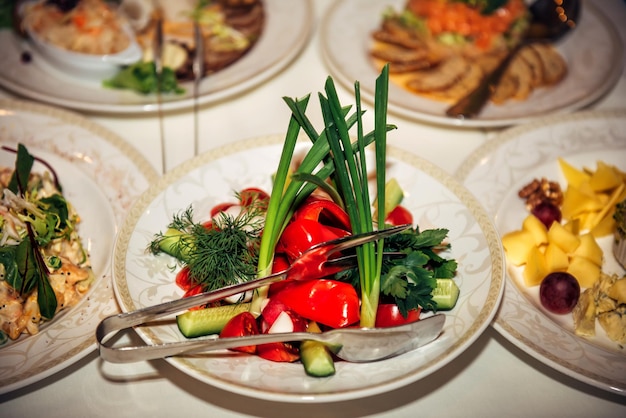 Portionierter Salat aus frischem Gemüse und Kräutern auf Platte Nahaufnahme Grob gehackte Gurken Tomaten Paprika Radieschen Bankett im Restaurant
