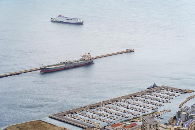 Porto de Gibraltar com grandes navios ancorados ao lado de pequenos barcos de recreio na marina