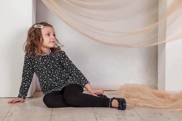 Porträt 5-6 Jahre altes Mädchen im Kleid sitzt am Kamin und schaut in die Kamera