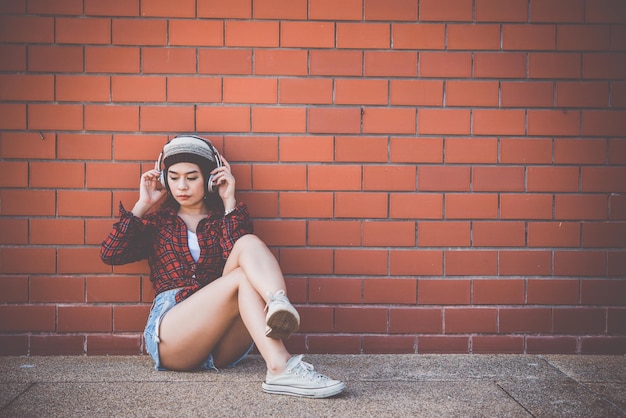 Porträt asiatisches Hipster-Mädchen auf BacksteinmauerhintergrundHippie-KleiderstilThailand moderne Frau LifestyleBeauty Fashion Portrait im Freien