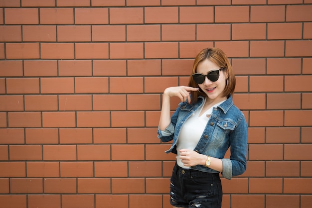 Porträt asiatisches sexy Hipster-Mädchen auf Backsteinmauer-Hintergrundmode-Konzeptthailand-Menschen