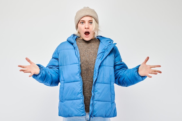 Foto porträt blonder junger frau mit glücklichem gesicht, freudig lächelnd mit erhobenen handflächen und schockiertem offenen mund, isoliert auf weißem studio-hintergrund.