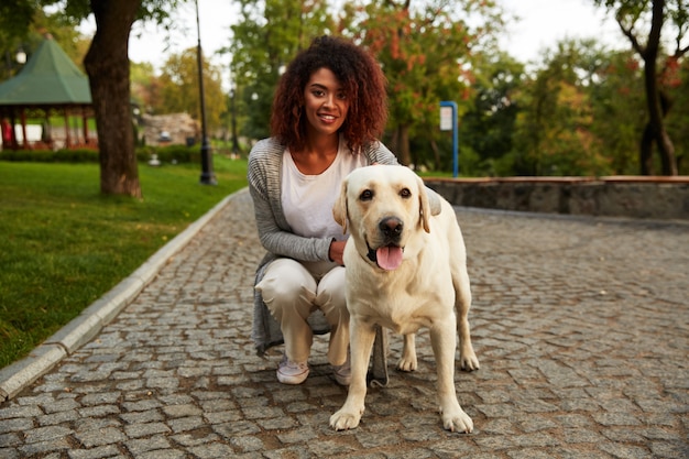 Porträt der afrikanischen Dame, die mit Hund im Park geht