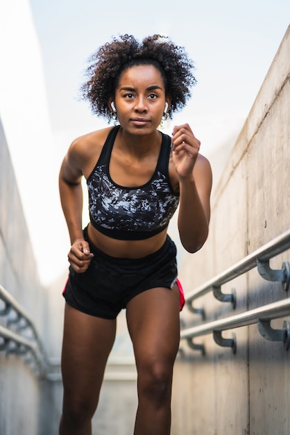 Porträt der Afro-Sportlerin, die im Freien läuft und Übung tut